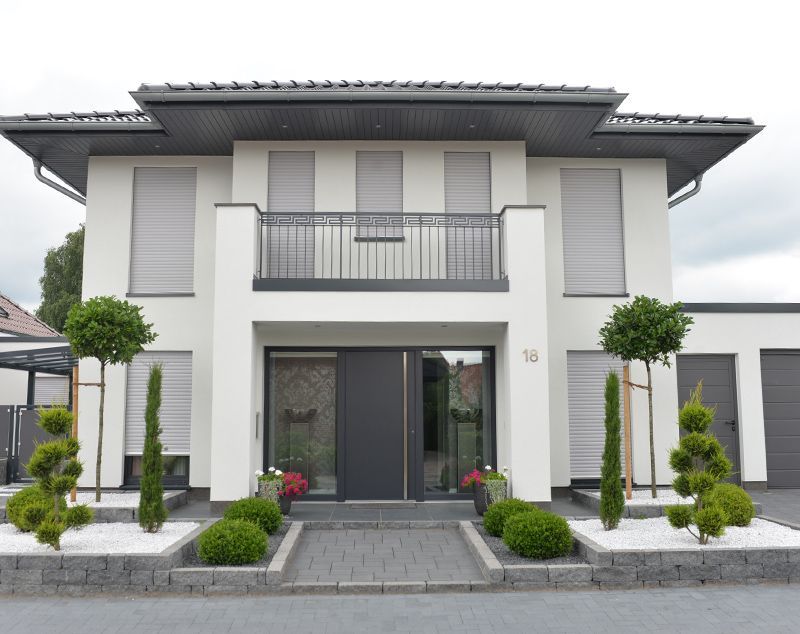 Ein großes weißes Haus mit einem Balkon und Bäumen davor.