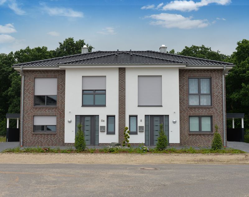 Ein weißes und braunes Backsteinhaus mit Fensterläden