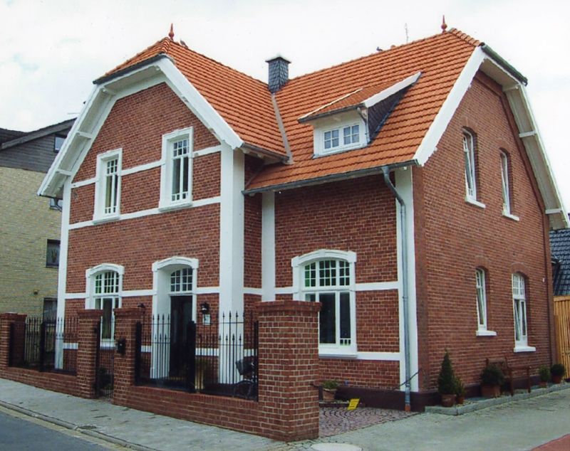 Ein großes rotes Backsteinhaus mit einem roten Ziegeldach
