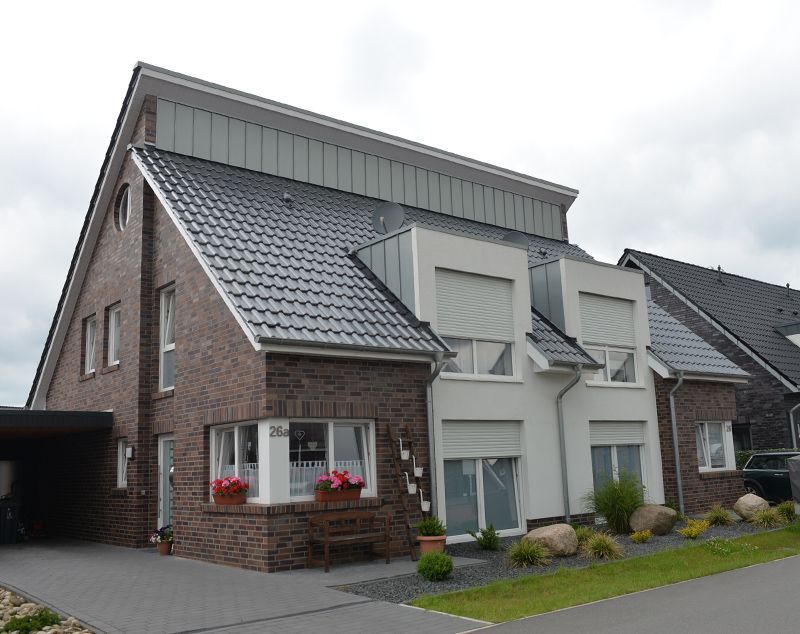 Ein Backstein-weißes Haus mit einem grauen Dach