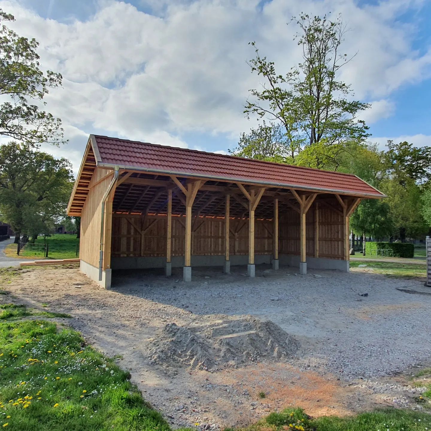 Ein Holzschuppen mit einem roten Ziegeldach