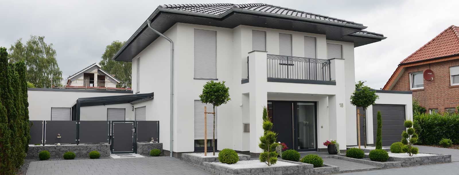 Ein großes weißes Haus mit einem Balkon und Bäumen davor.