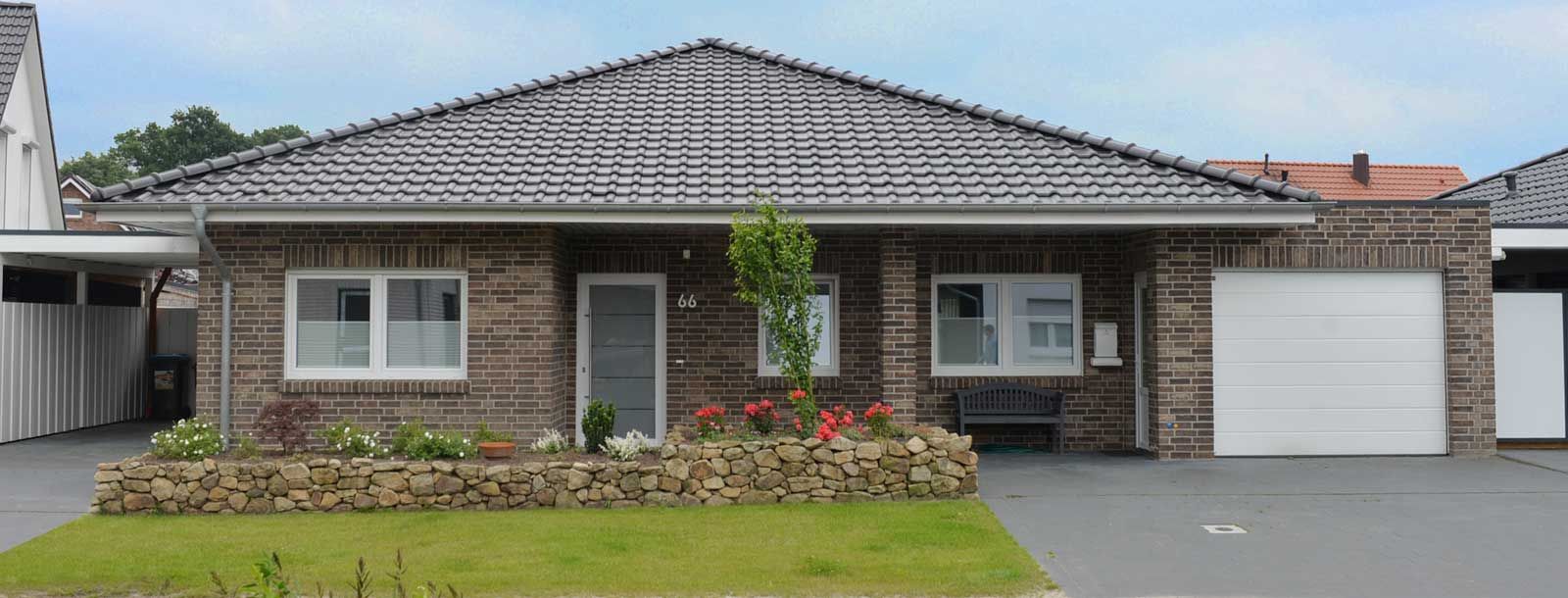 Ein Backsteinhaus mit grauem Dach und weißem Garagentor.