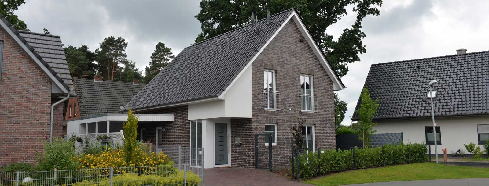 Ein Backsteinhaus mit grauem Dach ist von anderen Häusern umgeben.