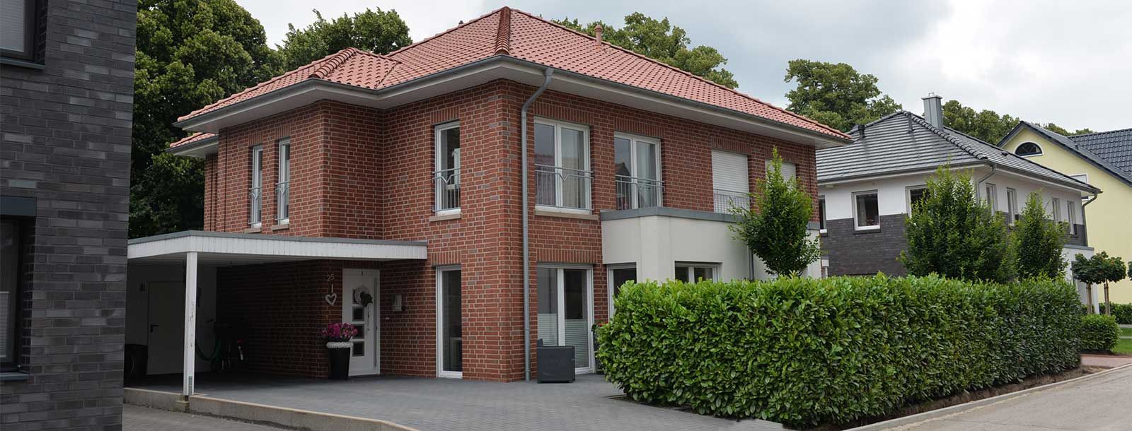 Ein Backsteinhaus mit rotem Ziegeldach und einem Carport davor.