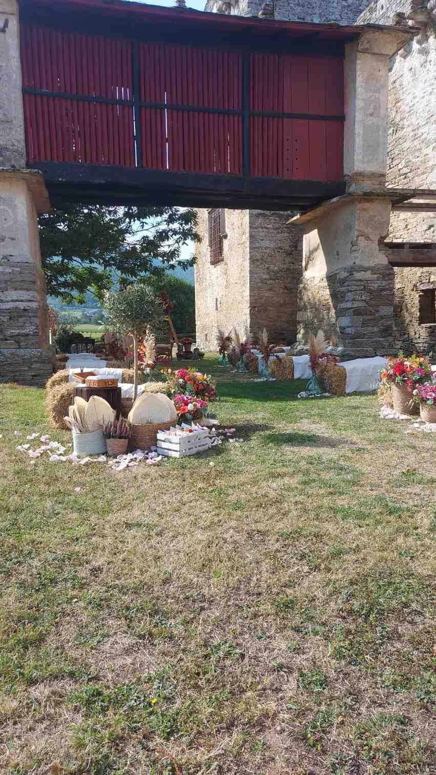 Arreglo nupcial bajo una gran puerta de madera. Fardos de heno y arreglos florales decoran la zona de césped.