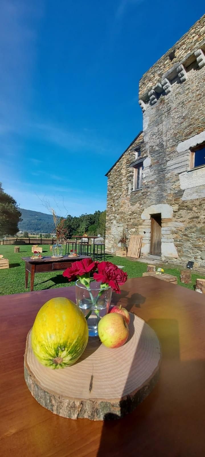Un bodegón de un limón y una manzana sobre una tabla de madera sobre una mesa frente a un edificio de piedra.