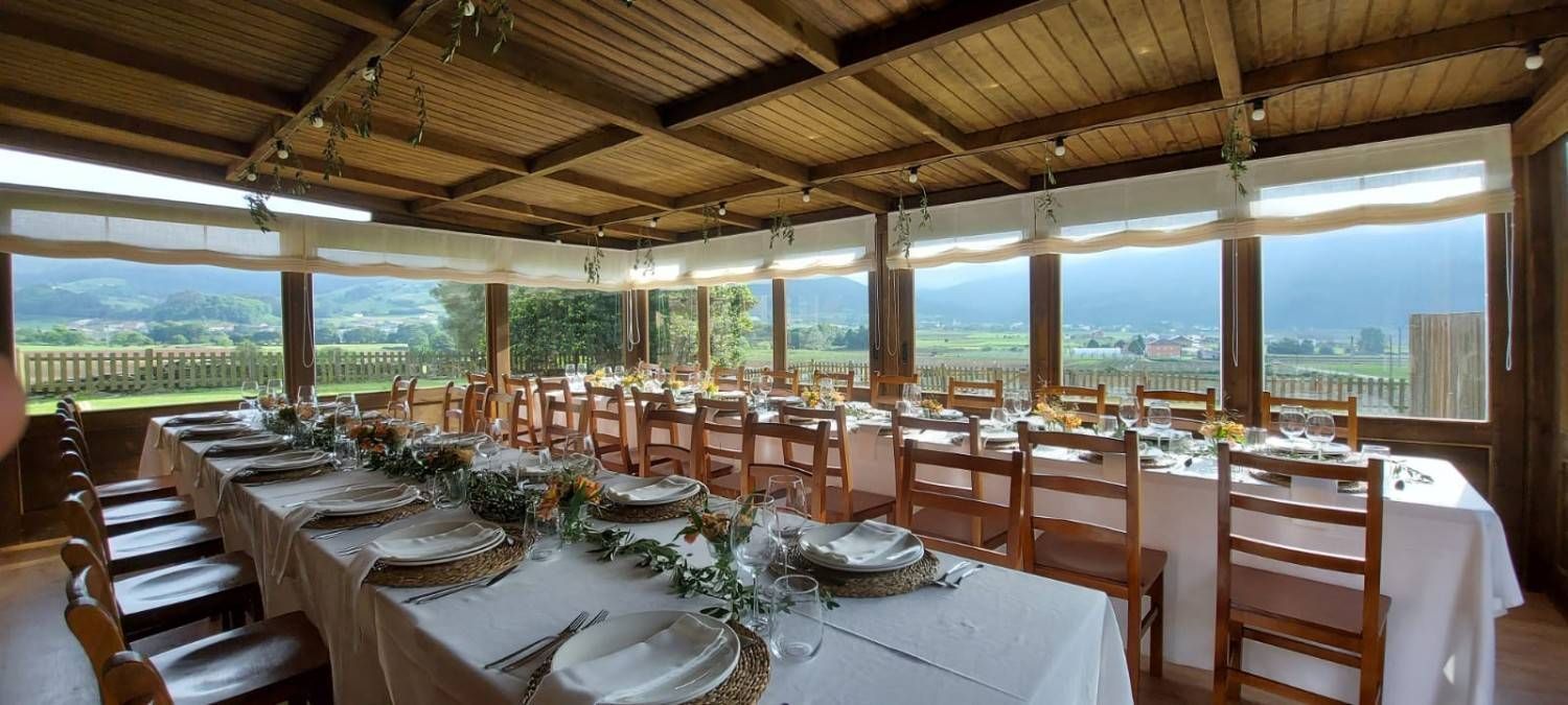 Un comedor con largas mesas preparadas para comer, vistas a las montañas a través de las ventanas.