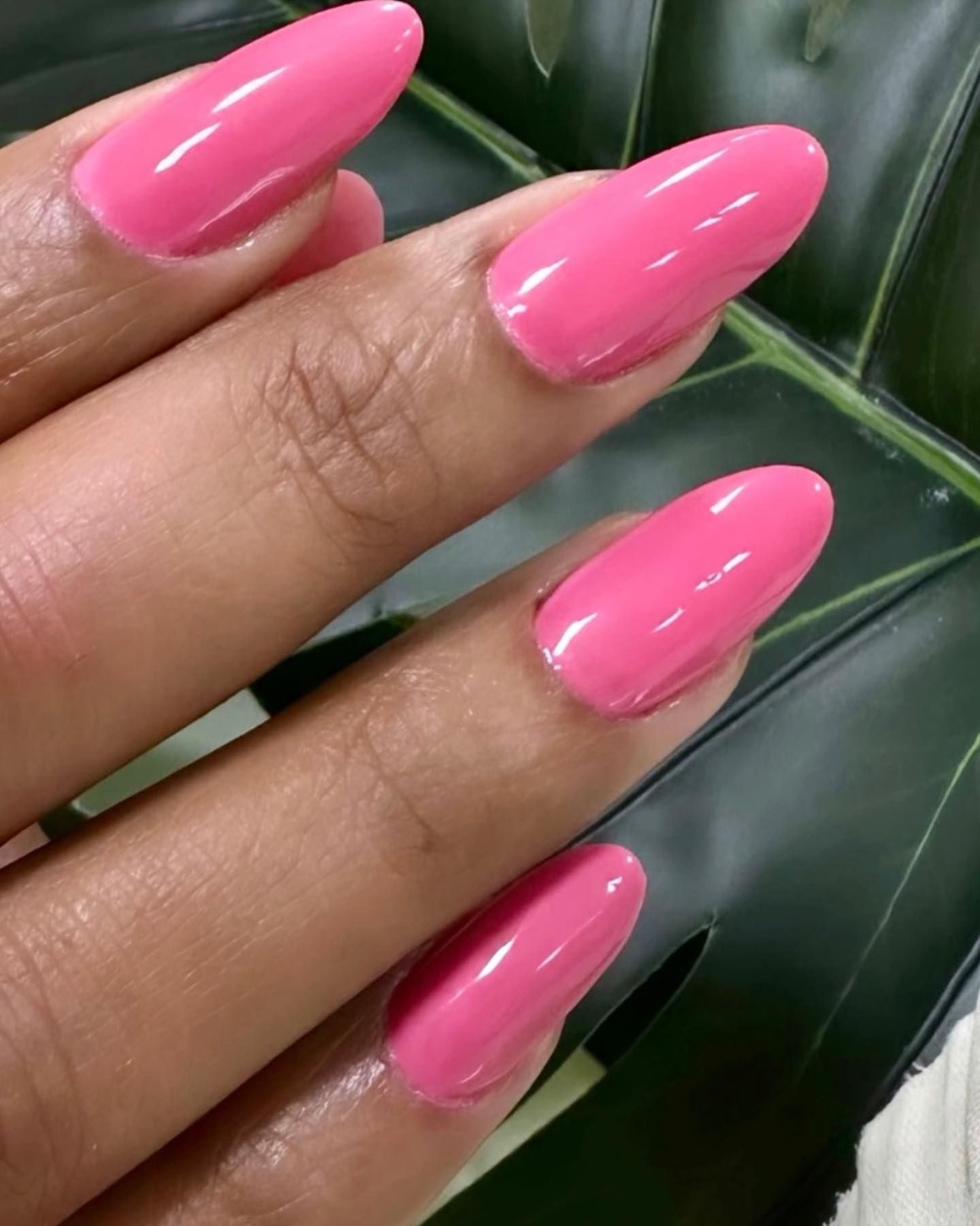 Esmalte de uñas rosa sobre uñas largas y almendradas.