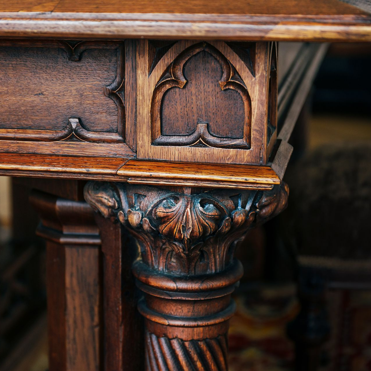 Pied de meuble en bois finement sculpté, avec des détails brun foncé et des panneaux décoratifs