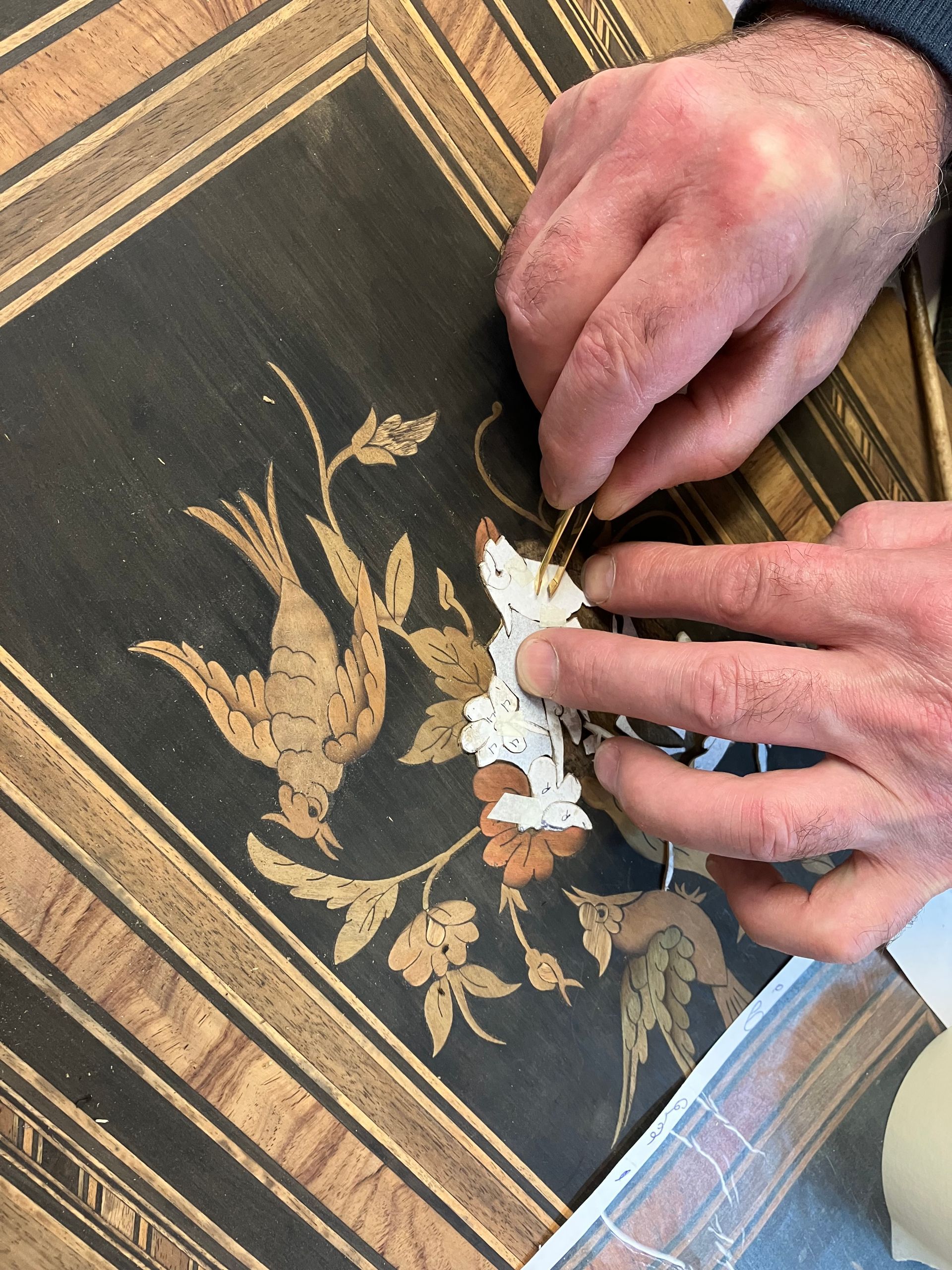 Des ciseaux à bois à manche en bois posés sur un établi usé, avec une brosse et des copeaux de bois à proximité