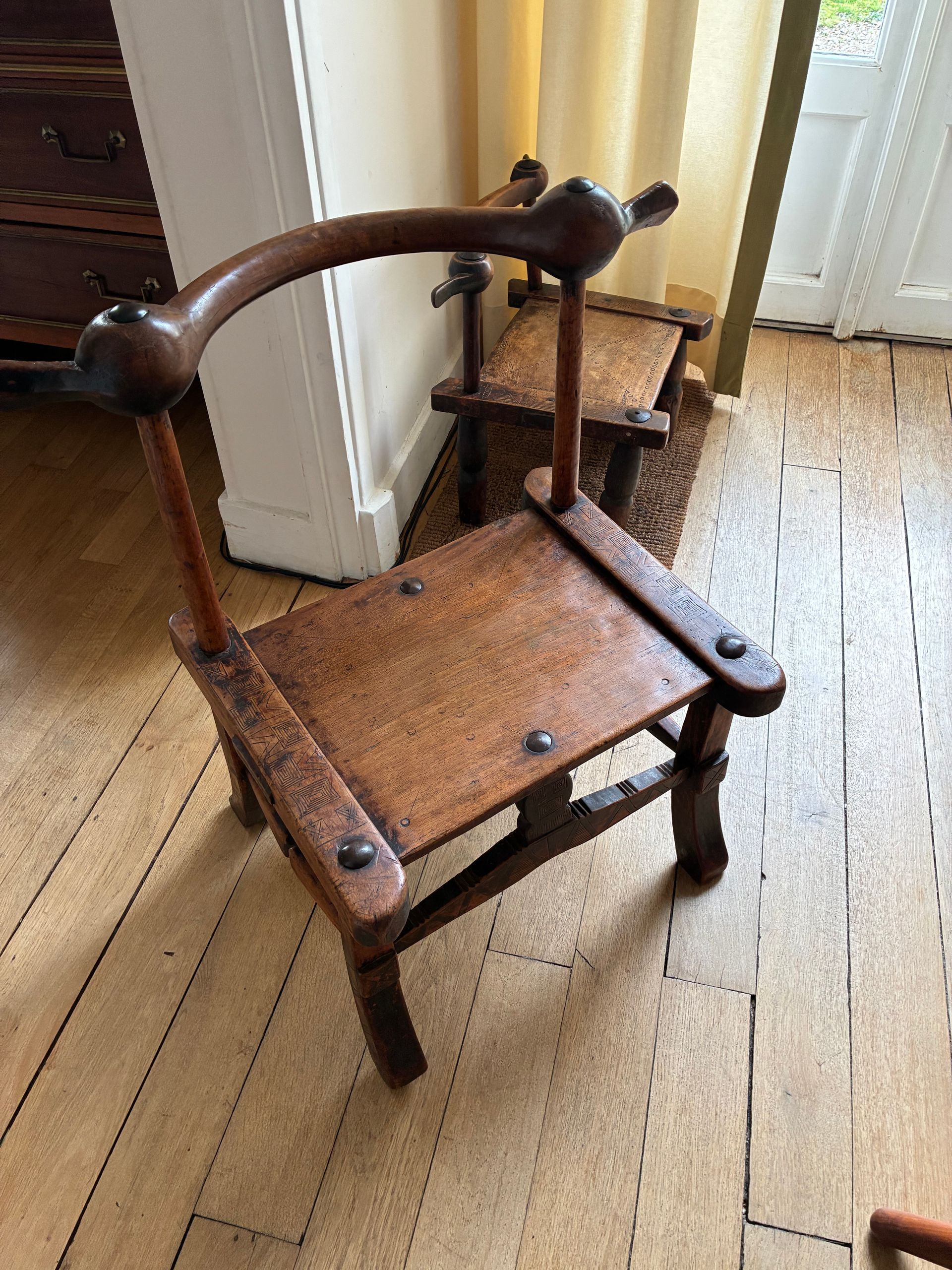 Commode en bois à tiroirs contre un mur blanc, ornée de verrerie bleue et d’une plante.