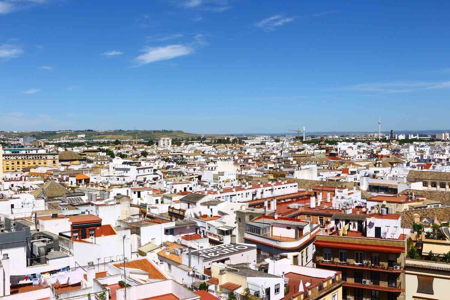 Paisaje urbano encalado con tejados de tejas rojas bajo un cielo azul brillante.