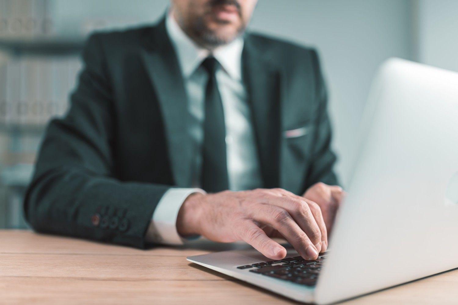 Un empresario tecleando en un portátil en un escritorio de una oficina.