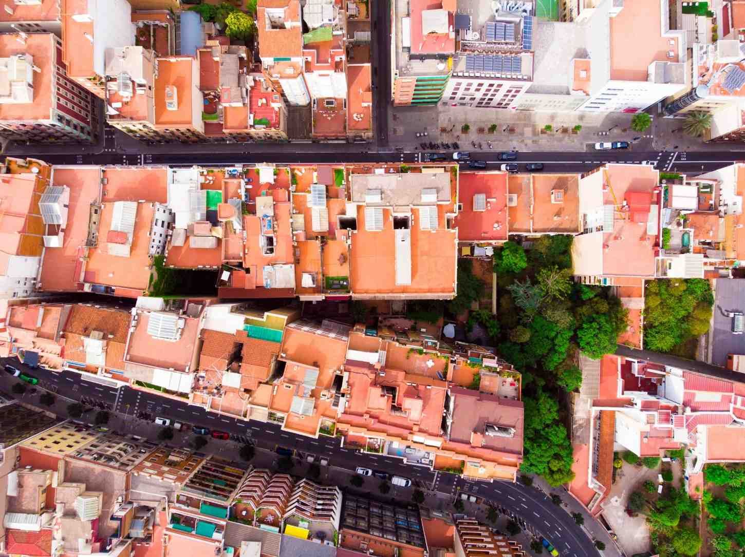 Vista aérea de un barrio densamente poblado con edificios de tejados rojos, calles estrechas y coches aparcados.