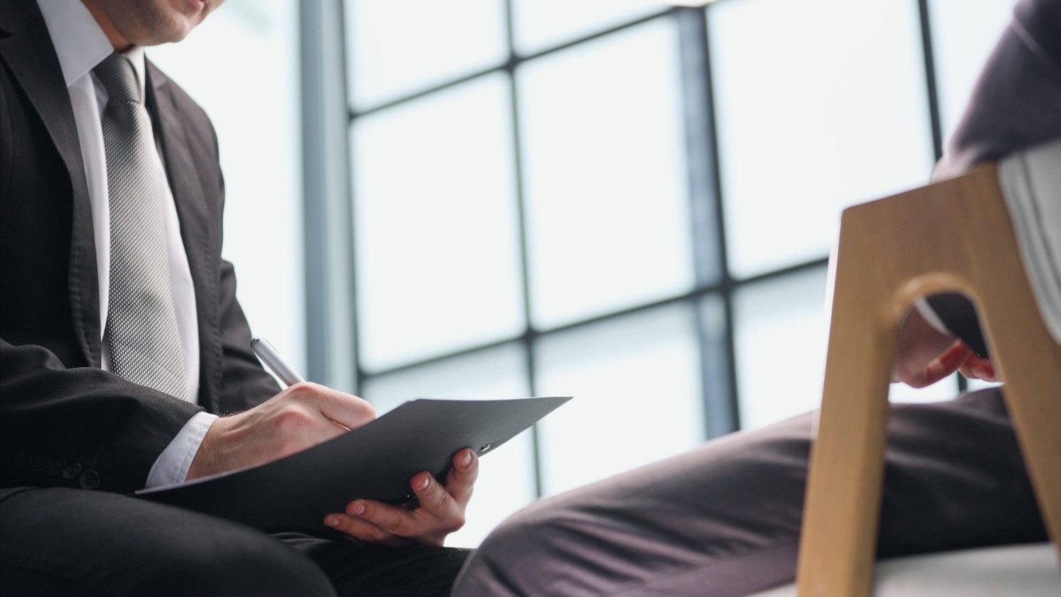 Dos hombres de negocios con traje discutiendo un documento en una luminosa sala de reuniones de oficina.
