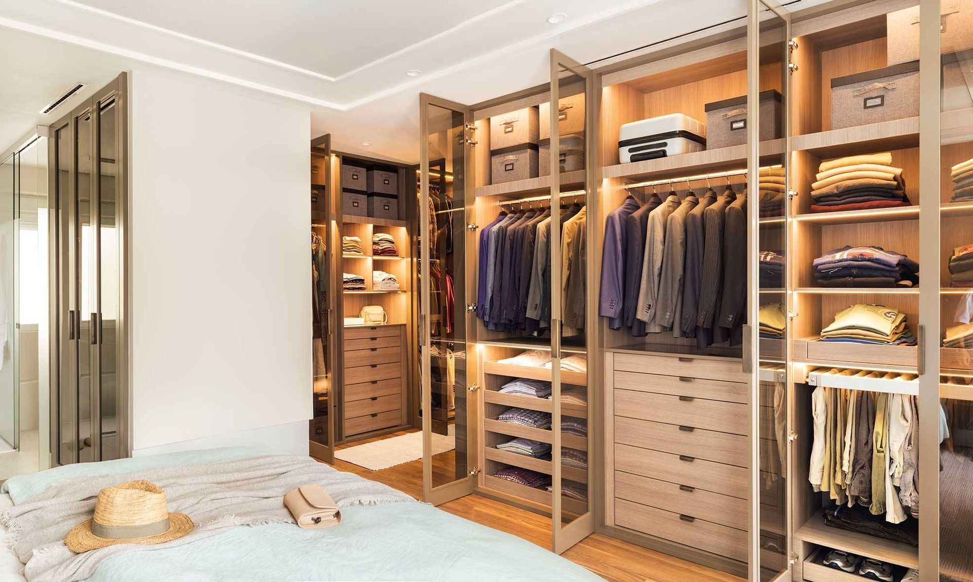 Vestidor con muebles beige y ropa, zapatos y accesorios organizados.