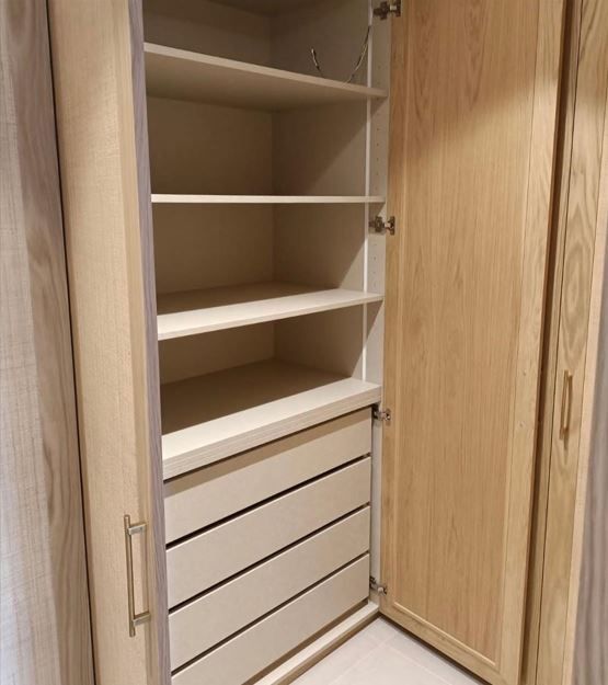 Una sala de estar vacía con pisos de madera y paredes blancas.