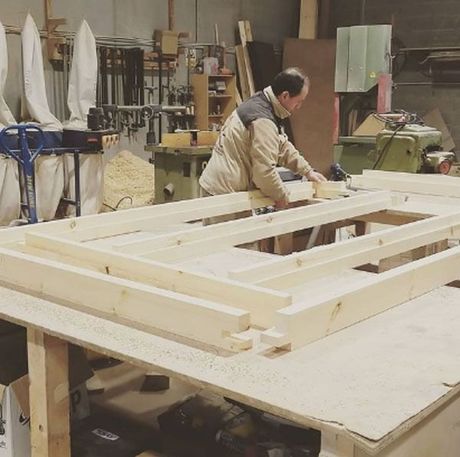Un hombre está trabajando en un trozo de madera en un taller.
