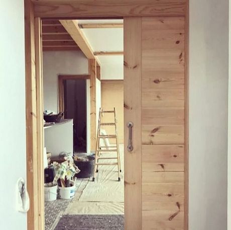 Una puerta de madera se abre a una habitación con una escalera.