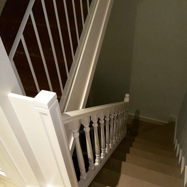 Una escalera con barandilla blanca que sube al segundo piso.