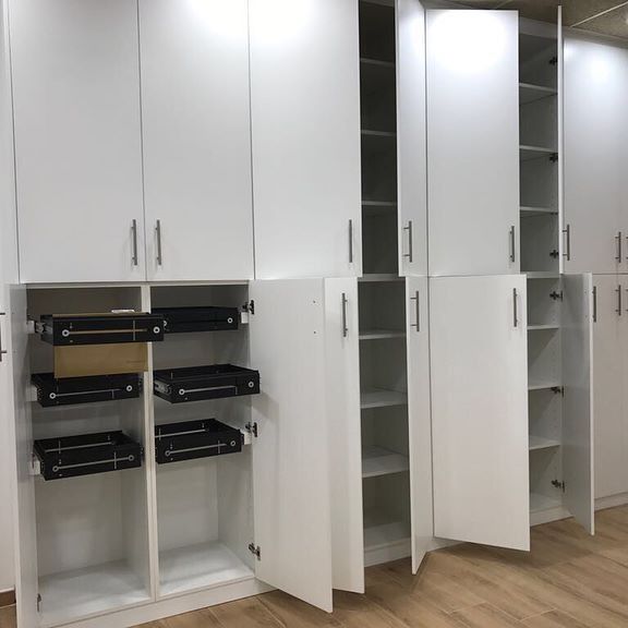 Una habitación con muchos armarios blancos con las puertas abiertas.