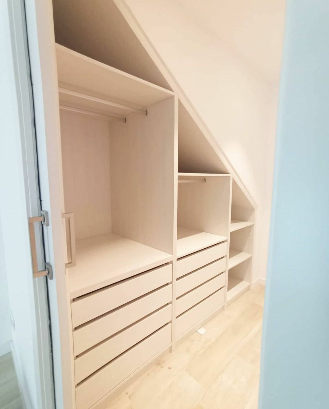 Un vestidor con techo inclinado y muchos cajones.