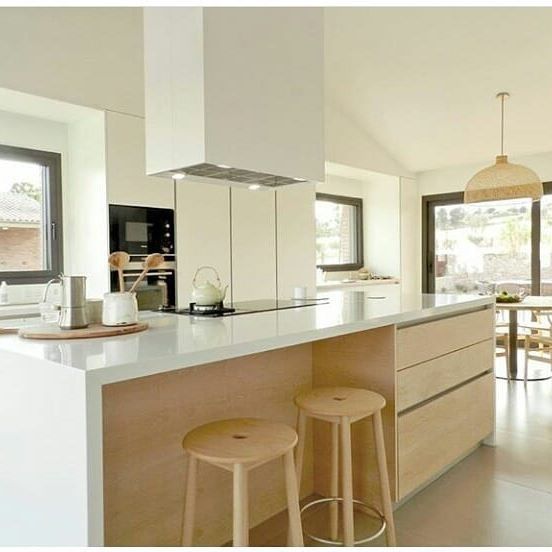 Una cocina con una gran isla y dos taburetes.