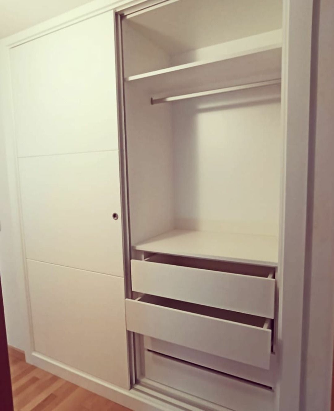 Un armario blanco con puertas correderas y cajones.
