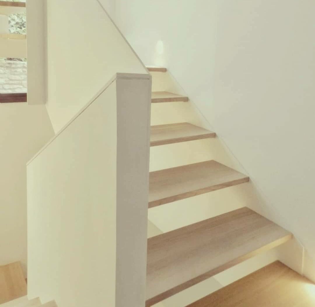 Una escalera con escalones de madera y barandilla blanca.