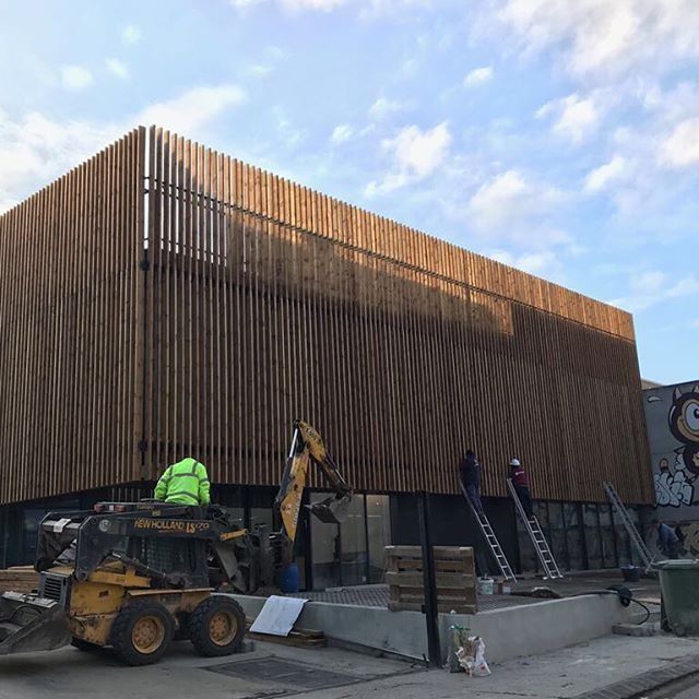Un tractor amarillo está estacionado frente a un gran edificio de madera.