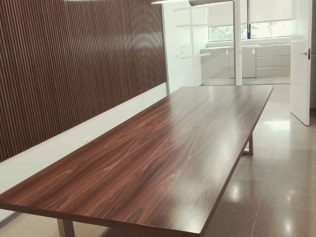 Una mesa larga de madera en una habitación con una puerta abierta.