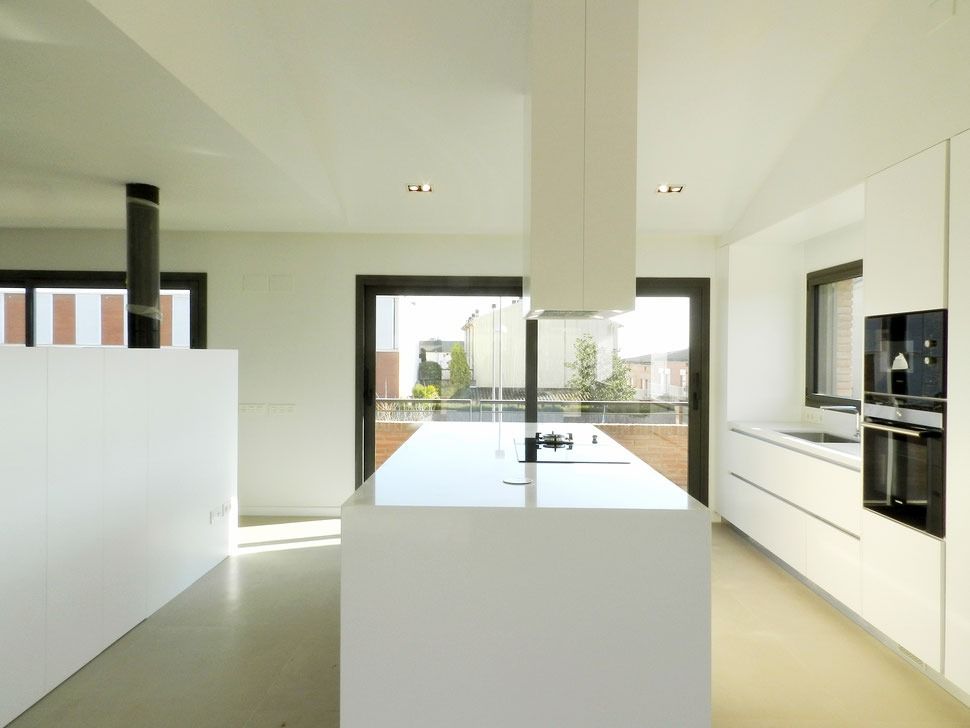 Una cocina con gabinetes blancos y una isla grande.