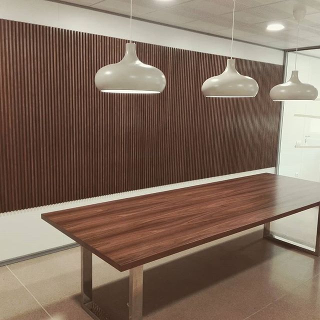 Una mesa de madera en una habitación con tres lámparas colgantes que cuelgan del techo.