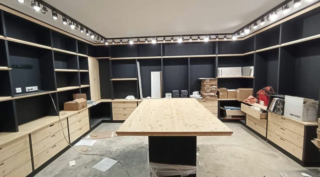 Una habitación grande con muchos estantes y una mesa de madera.