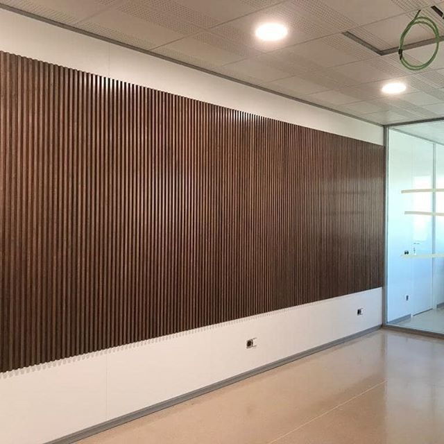 Una habitación con una gran pared de madera y una puerta de cristal.