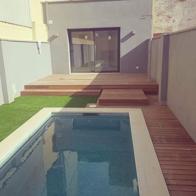 Una pequeña piscina en un patio trasero con una terraza de madera.