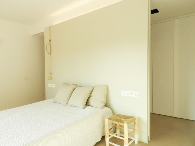 Un dormitorio con una cama y un taburete dentro.