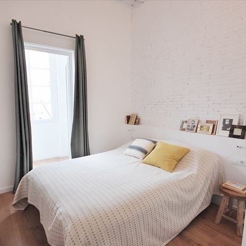 Un dormitorio con una cama y una ventana con cortinas.