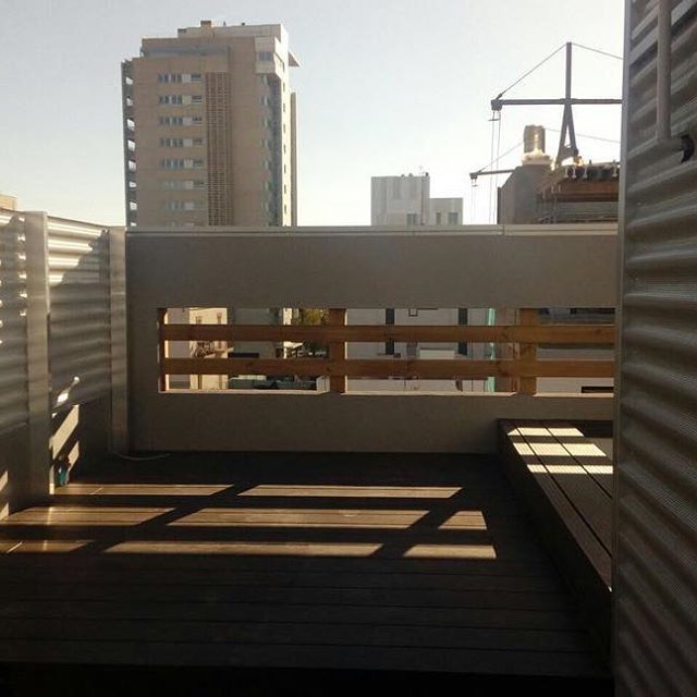 Un balcón con barandilla de madera y vista a la ciudad.