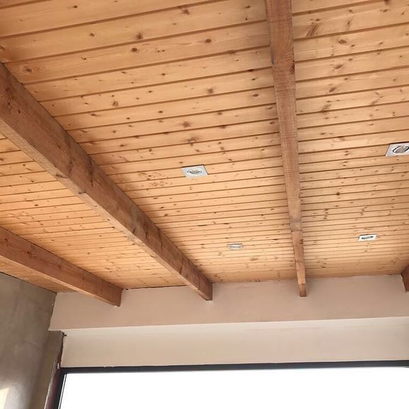 Un techo de madera con vigas en una habitación con ventana.