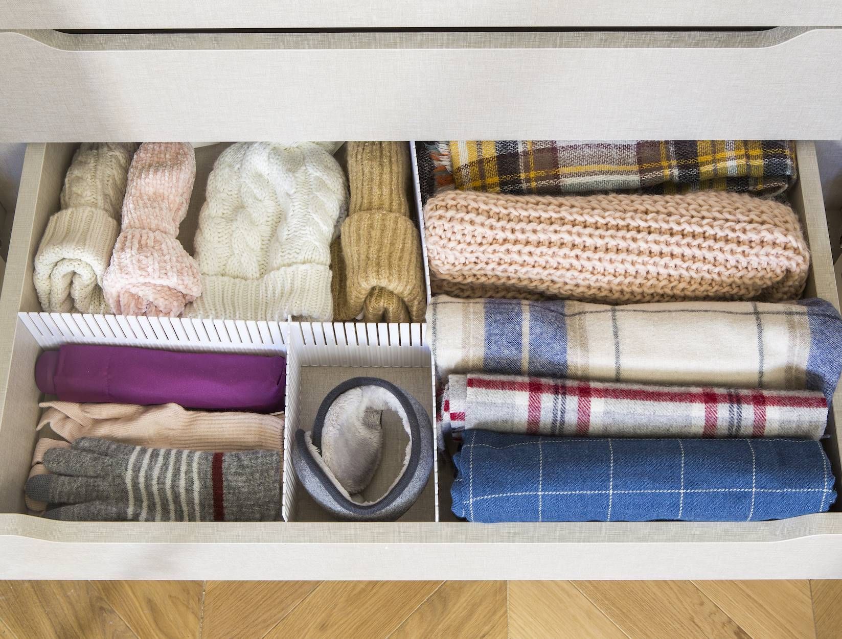 Cajón organizado con prendas de vestir, incluidos sombreros, bufandas y guantes en compartimentos separados.