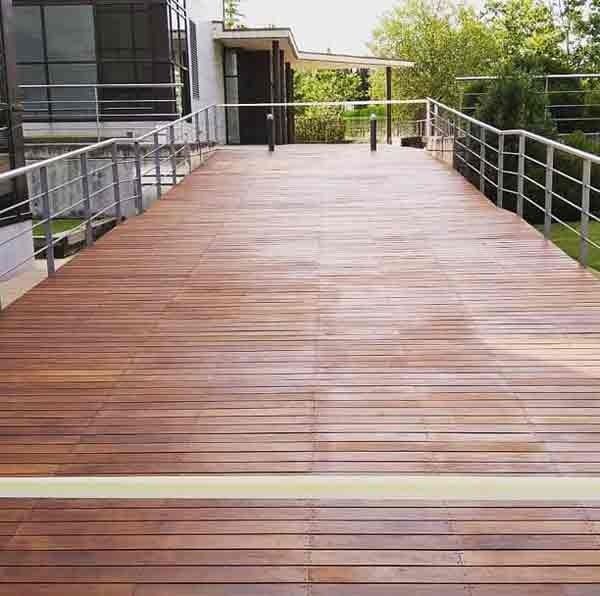 Una terraza de madera con una barandilla de metal que conduce a una casa.