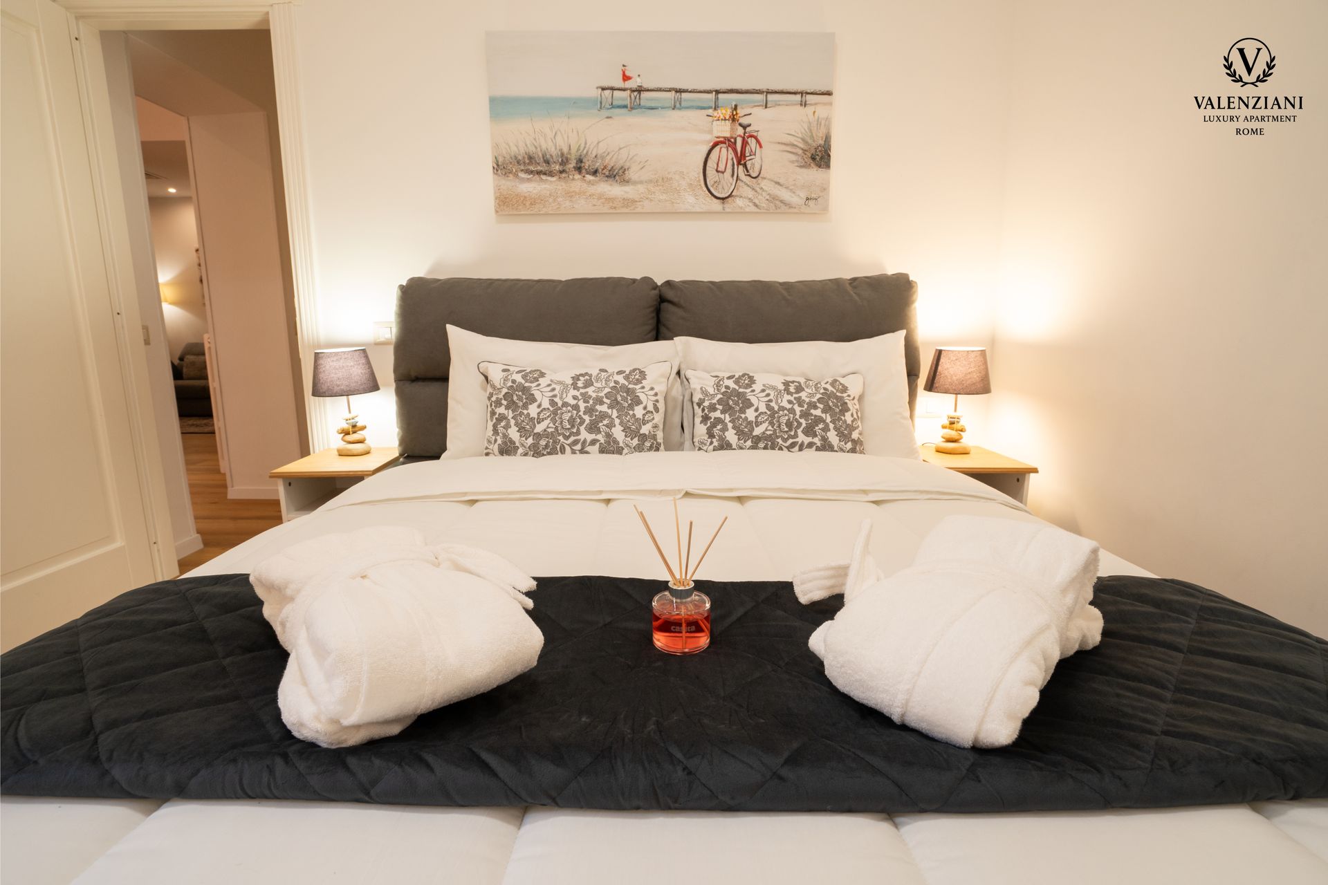 Bedroom with white walls, gray headboard, beach artwork, and bed with gray and white linens.