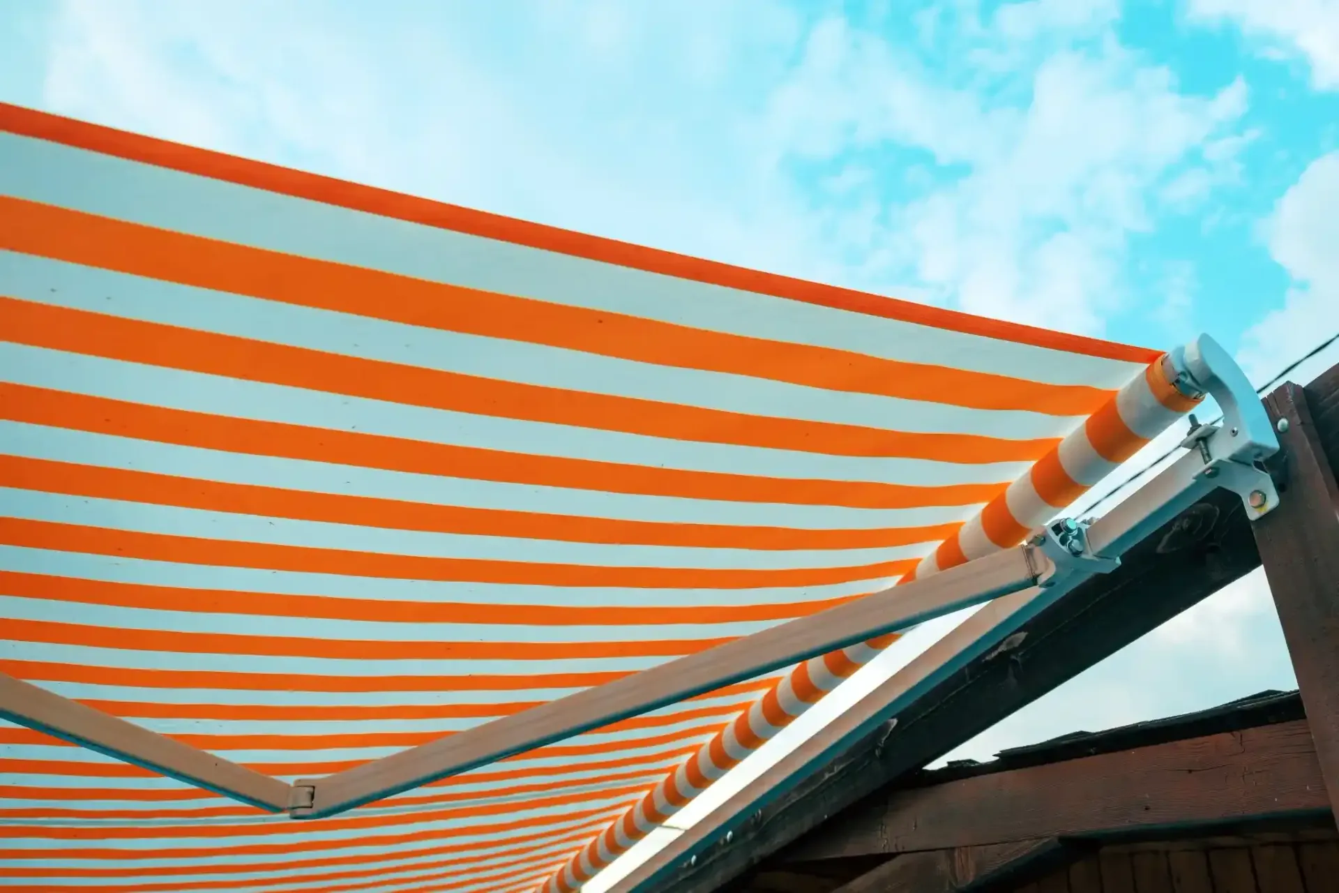 Un toldo de rayas naranjas y blancas se extendía contra un cielo azul parcialmente nublado.