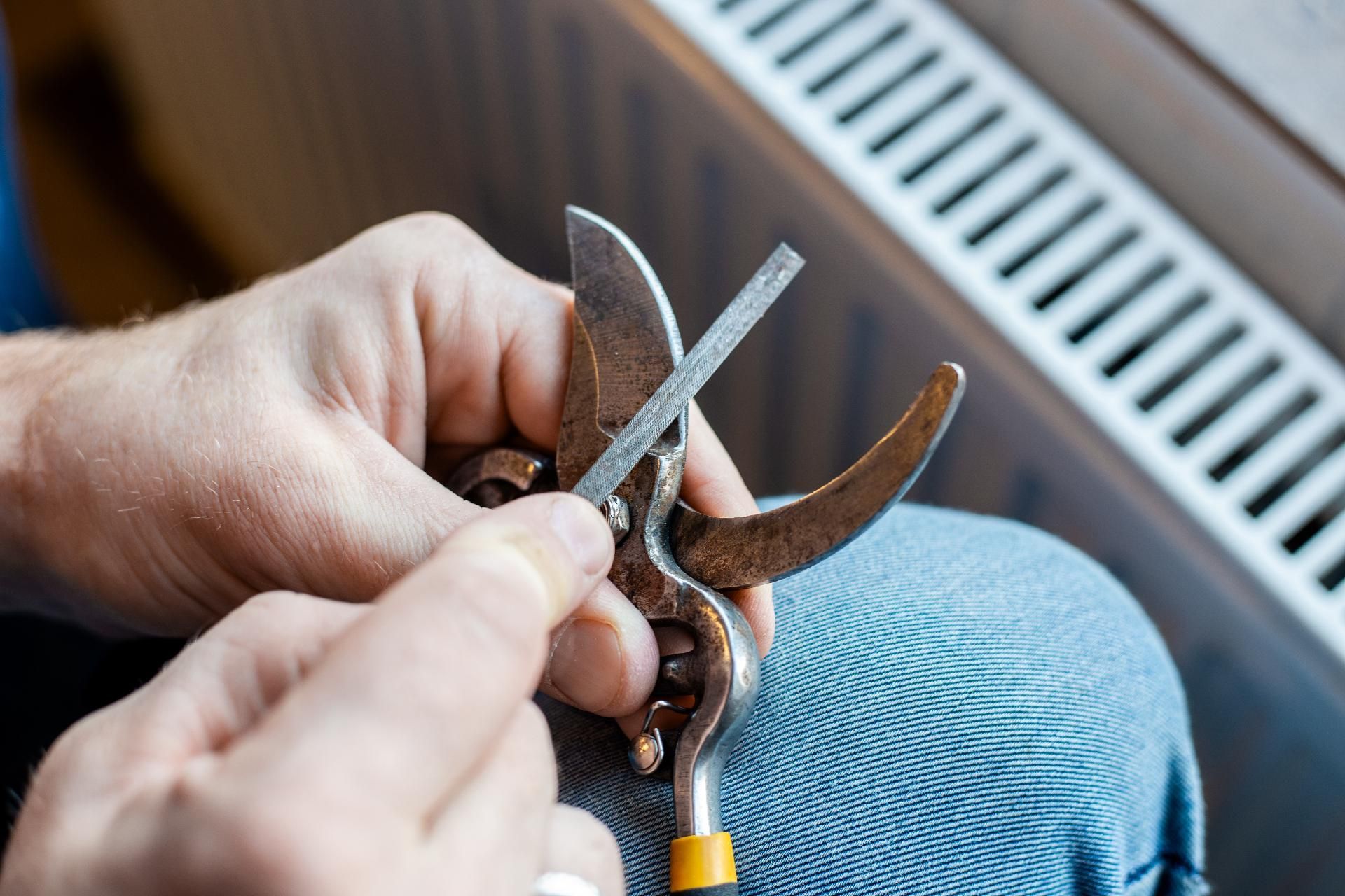 Hand hält Werkzeug nahe Heizkörper, Kleinreparatur an Heizungsventil