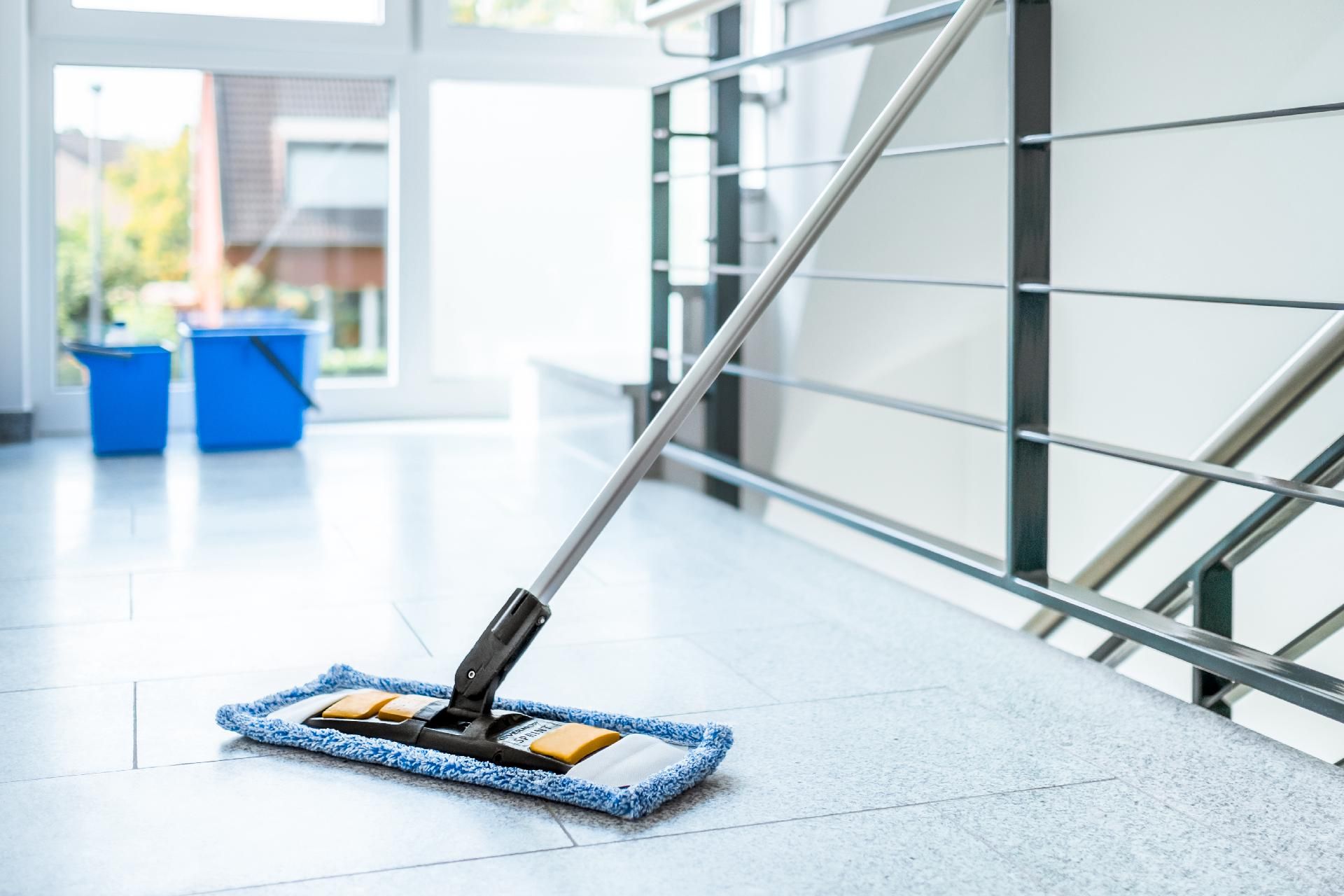 Bodenreinigung im Innenbereich mit Wischmopp Bodenreinigung im Innenbereich mit Wischmopp in modernem Gebäude