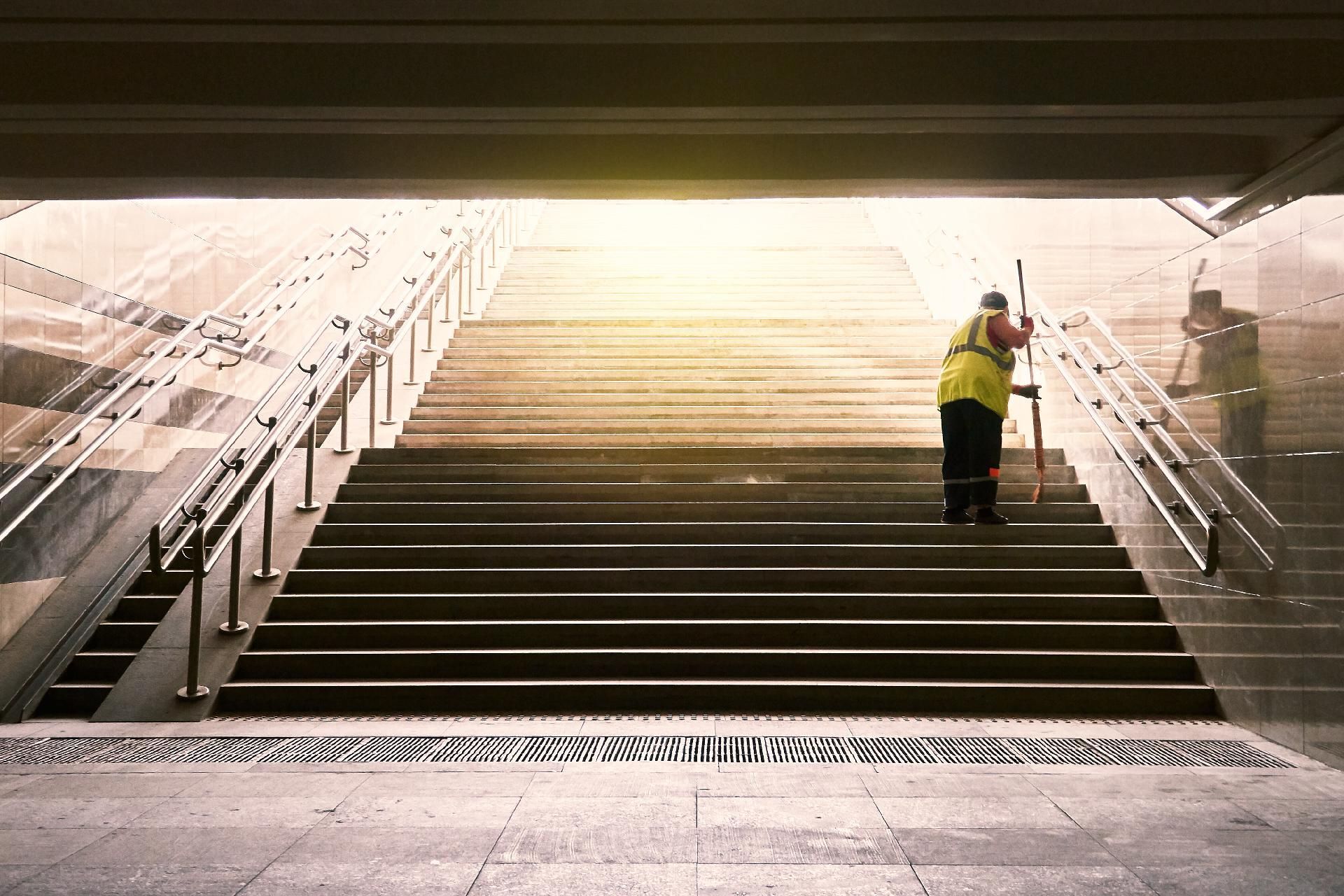 Person reinigt Treppe in großem Gebäude mit Reinigungsgerät