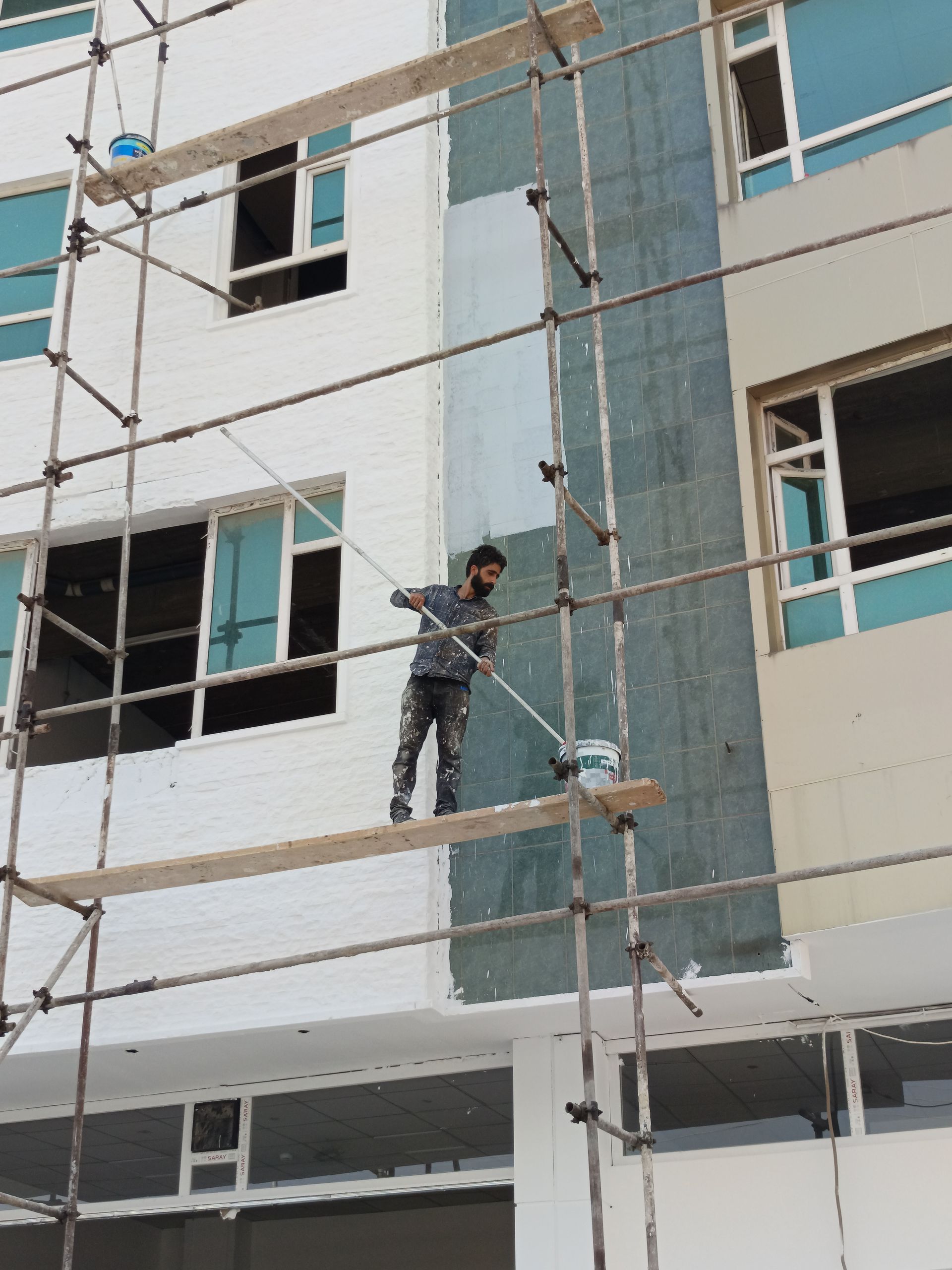 Dos trabajadores con cascos inspeccionan la pared de un pasillo; uno de ellos marca la zona cercana a un interruptor de luz.