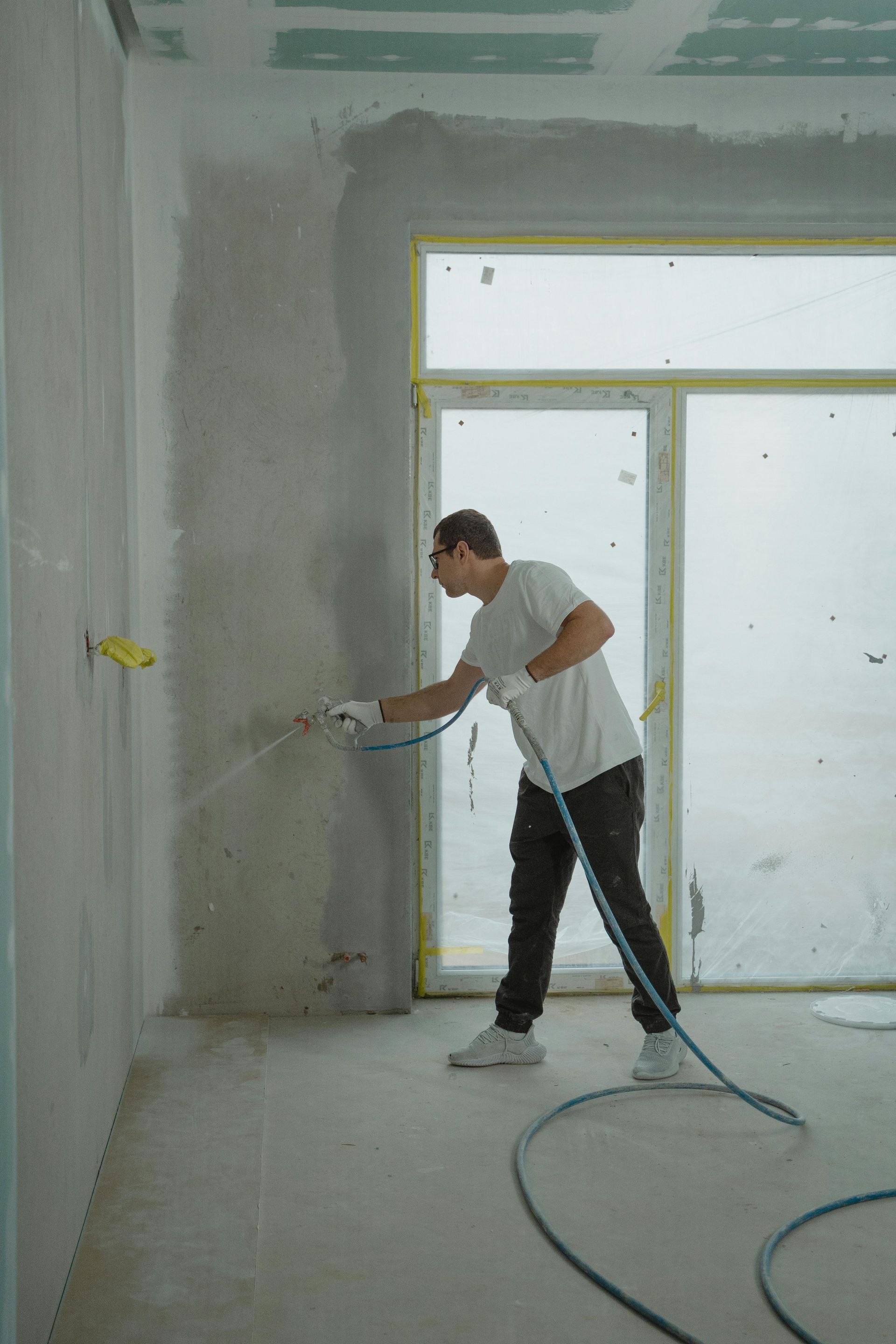 Un trabajador aplica yeso en la pared interior de una habitación en obras.
